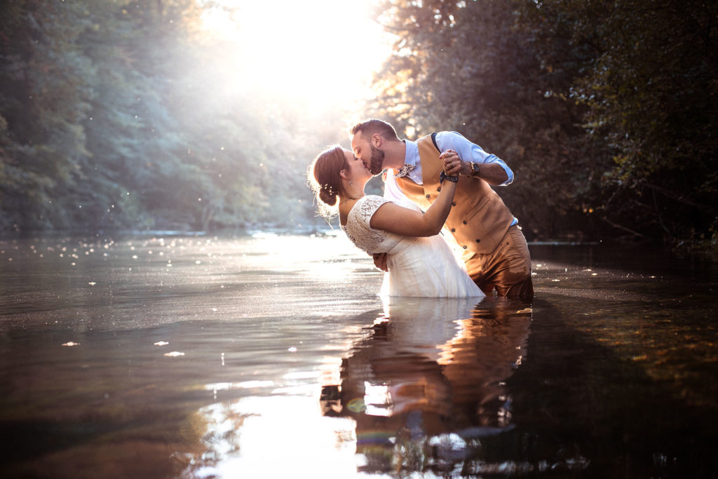 photo mariage de couple qui s'embrasse au milieu de l'eau dans une lumière de fin d'après-midi d'automne